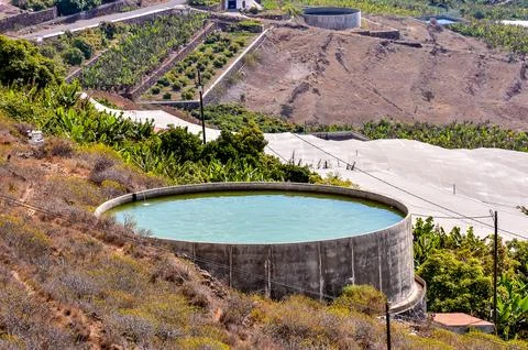 A large, circular pool of water sits on a hillside Stock Photos
