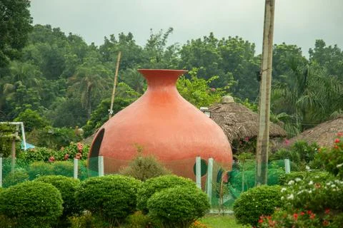 Large clay pitcher structure nestled among lush greenery in garden. Stock Photos