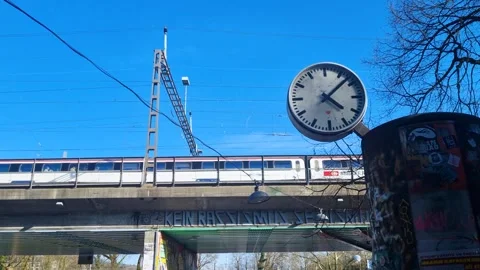 A large clock hangs in front of a train bridge under a clear blue sky, Bern Stock-Footage 305225555