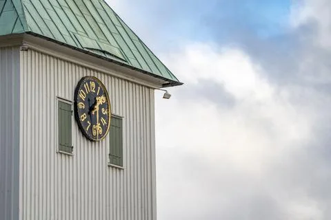 A large clock mounted to the side of a church building in Kungalv Stock Photos