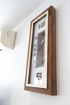 A large clock mounted on a white wall Stock Photos