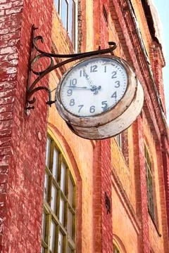 A large clock on the red brick wall of a production building. Stock Photos