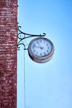 A large clock on the red brick wall of a production building. Stock Photos