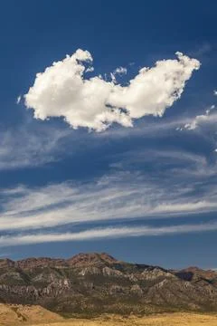 A large cloud drifts over rugged Utah mountains, framed by streaks of high-.. 写真素材