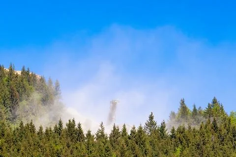A large cloud of dust rising from a stone quarry within a mountain forested area Stock Photos