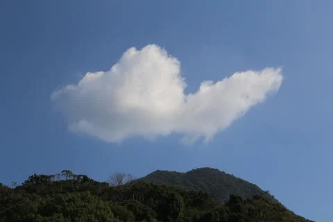 A large cloud is floating in the sky above a mountain Stock Photos