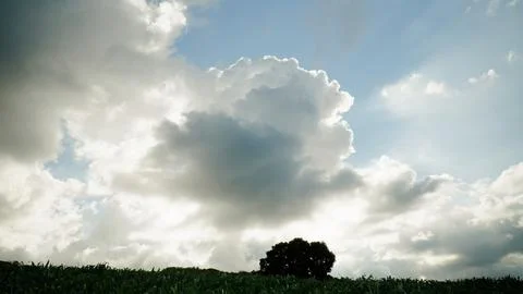 A large cloud is in the sky and the sun is shining through it Stock Photos