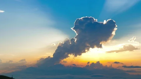 A large cloud of unusual shape against a blue sky and sunny sunset. Stock-Footage 117415269