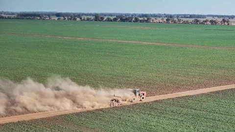 Large clouds of dust come off a tractor pulling a small road grader on Stock Footage 276971456