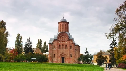 Large clouds float above the brown church, people walk in the park Vídeo Stock 73924375