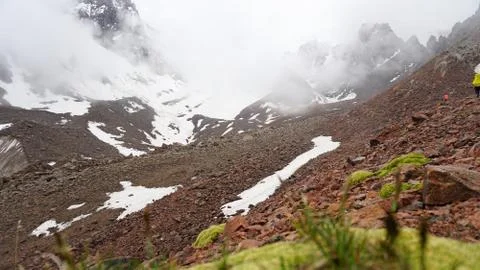 Large clouds swim through the gorge. A group of climbers climbs the peak. Stock Photos