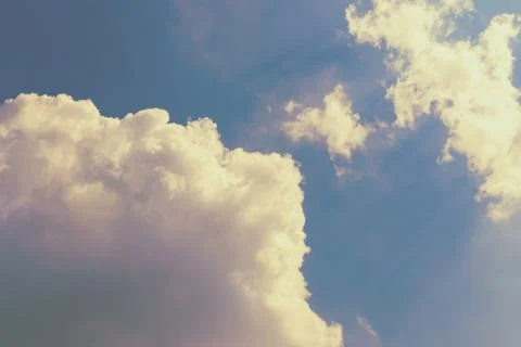 Large clouds toned in pink on a blue sky, lit by the sun. Abstract sky. Stock Photos