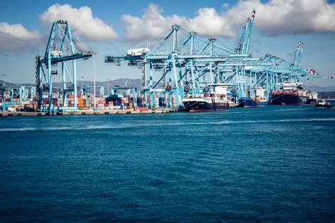 Large CMA CGM container ship unloading cargo under gantry cranes at port of.. Stock Photos