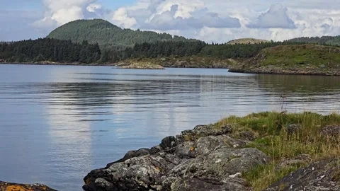 Large Coastal Rocks in Foreground with Dark Distant Shoreline and Forest Video stock 344895702
