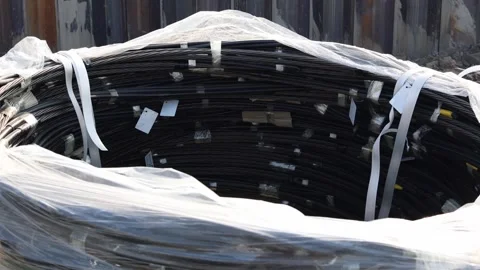 Large coil of industrial black cables tightly packed and wrapped in transparent  Stock Footage 314979121