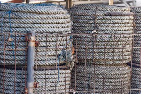 Large Coiled Nautical Ropes Stored Behind Metal Fence Stock Photos