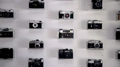Large collection of old cameras on white wall. various vintage photo cameras Stock Footage 148998585