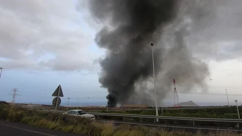 Large column of black smoke coming from a big fire in a car depot in Tenerife 4k Stock Footage 168718613