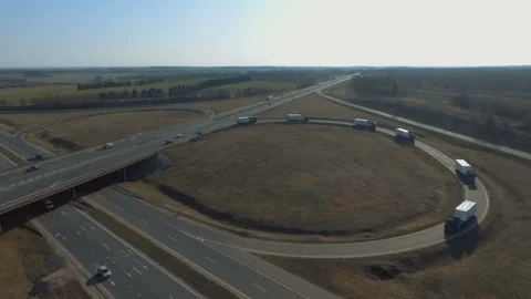 A large column of trucks moves around the ring and slides under the bridge Stock Footage 131234347