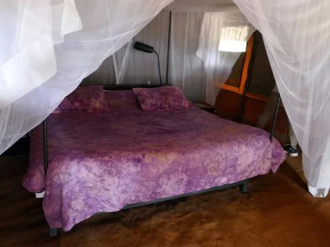 Large comfortable bed standing inside a tent Stock Photos