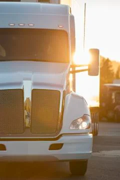 A large commercial truck moving through a truck stop parking lot at sunset. Stock Photos
