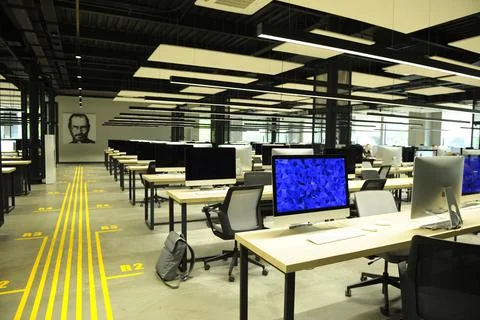 Large computer room with laptops on tables, blurred people working Stock Photos