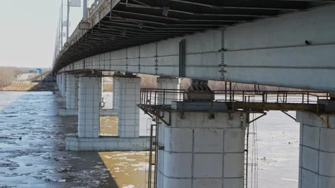 Large concrete bridge pillars over muddy river with floating ice Stock Footage 332432082
