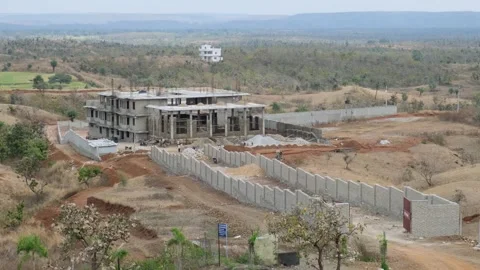 Large concrete building under construction in a vast rural mountain landscape Stock Footage 329541673