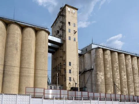 Large concrete grain elevator building against a clear blue sky, industrial a Stock Photos