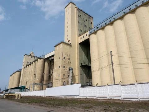 Large concrete grain elevator building against a clear blue sky, industrial.. Stock Photos