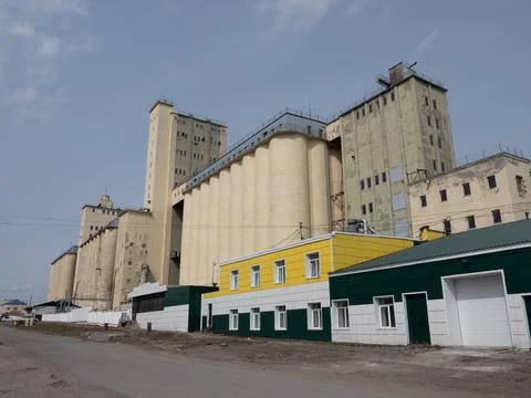 Large concrete grain elevator building against a clear blue sky, industrial.. Stock Photos