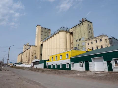 Large concrete grain elevator building against a clear blue sky, industrial.. Stock Photos