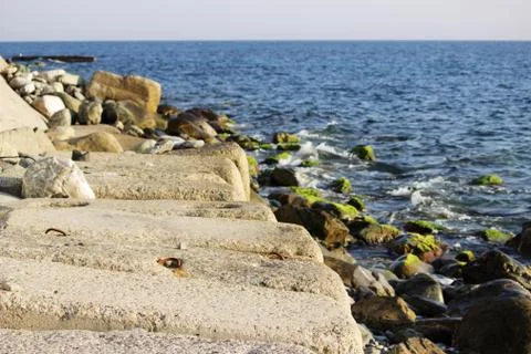 Large concrete rectangular blocks to protect the shore from erosion lie in th Stock Photos