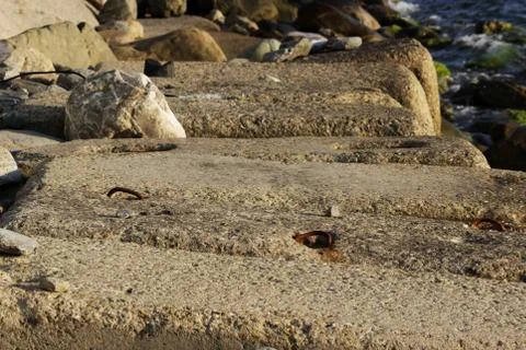 Large concrete rectangular blocks to protect the shore from erosion lie in th Photos