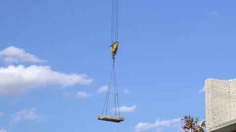 A large construction crane against the sky carries a load of concrete Stockbeeldmateriaal 143133282