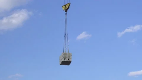 A large construction crane against the sky carries a load of concrete Stock Footage 143562084