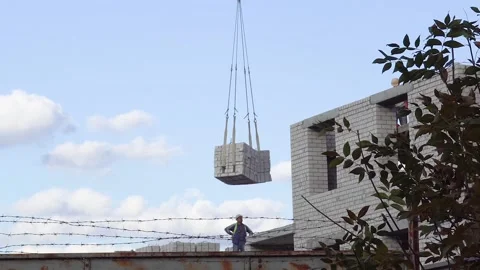 A large construction crane against the sky carries a load of concrete. The Stock-Footage 159485010
