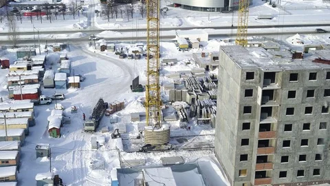 A large construction crane carries a concrete slab near the unfinished building Vídeos de archivo 73254496