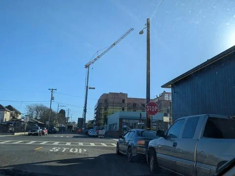 Large construction crane lifting materials over wooden building frame 库存照片