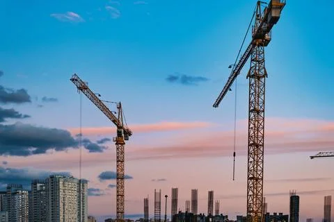 Large construction site with cranes working on a building complex, with sunset Foto stock