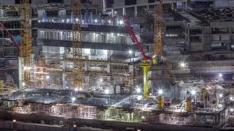 Large construction site with many working cranes night timelapse. Stockfoto's