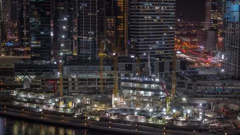 Large construction site with many working cranes night timelapse. Stockfoto's