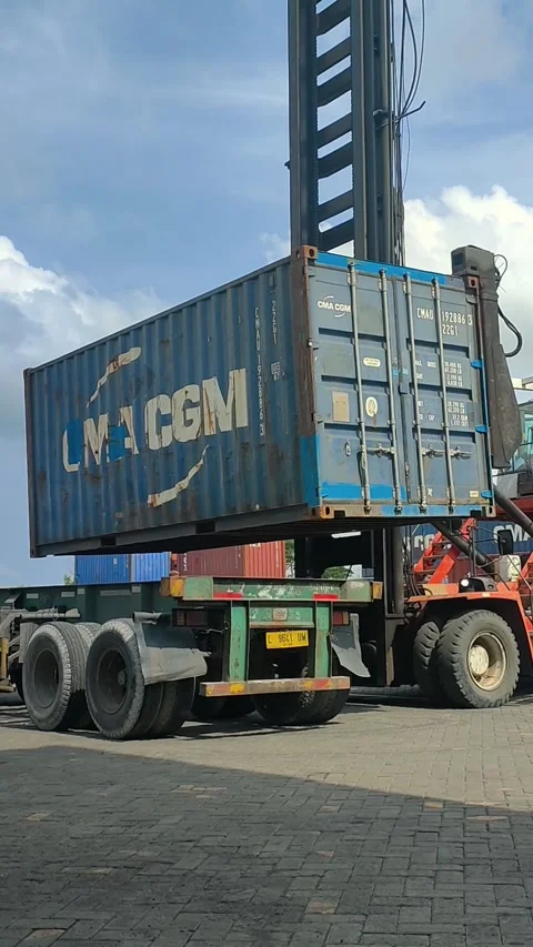 A large container is being carefully lowered from a crane onto a waiting tru Stock Footage 299620741
