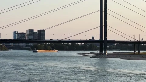 Large container cargo boat sail on Rhine river with vehicle traffic on bridge Stock Footage 321308078
