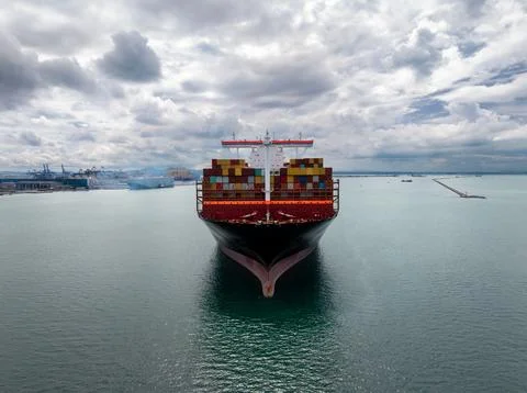 Large Container Ship Approaching Commercial Harbor Under Overcast Sky Lands.. Foto stock