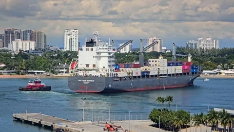 Large container ship being assisted by a tugboat in a coastal city harbor Stock Footage 341908797