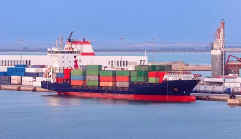 Large container ship in the cargo port of Cadiz at sunset. Stock Photos