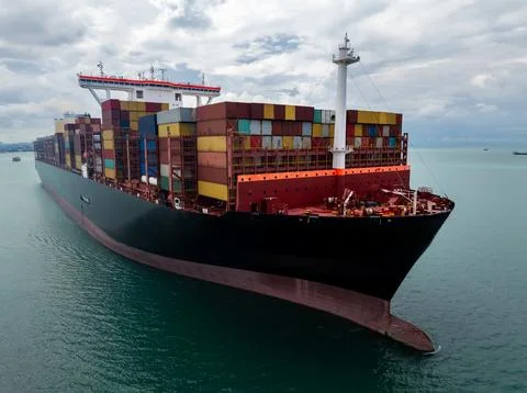 Large Container Ship Carrying Cargo Across Calm Sea Under Overcast Sky High.. Stock Photos