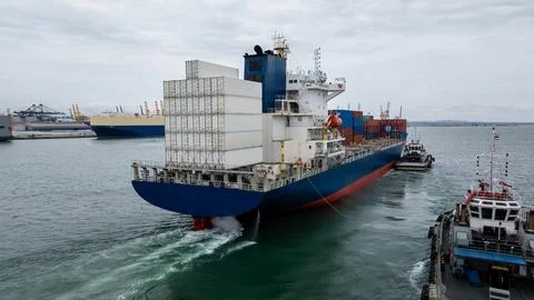 Large Container Ship Entering Harbor With Tugboat Escort At Laem Chabang Po.. Stock Photos