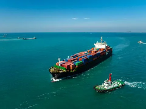Large Container Ship Escorted By A Tugboat Traveling Through The Open Sea I.. Foto stock
